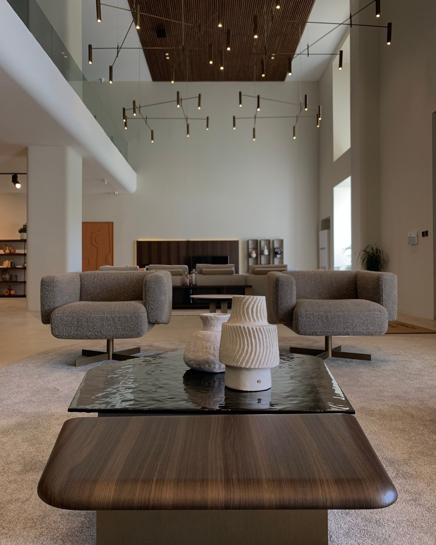 Salón amplio y luminoso de techos altos con butacas tapizadas y mesa de madera